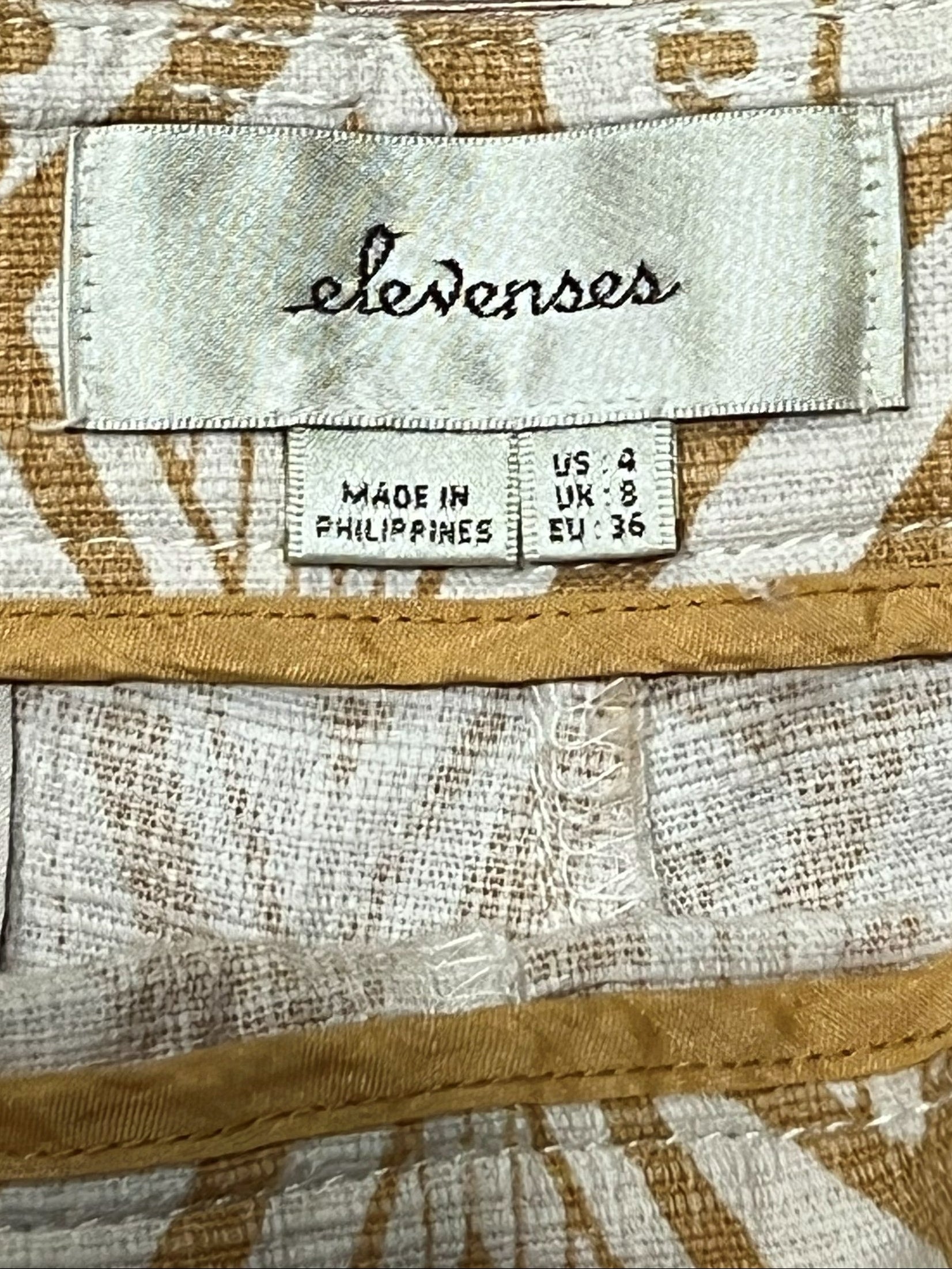 Close-up of a patterned garment fabric with a visible sewn-in label reading 'elevenos'.