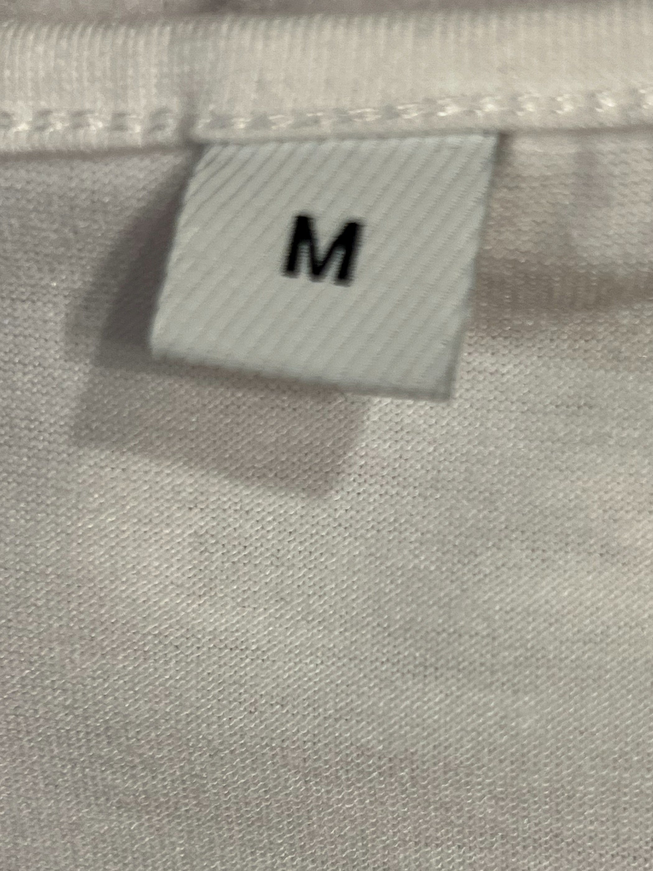 Close-up of a white fabric garment showing a sewn-on size tag with the letter M.