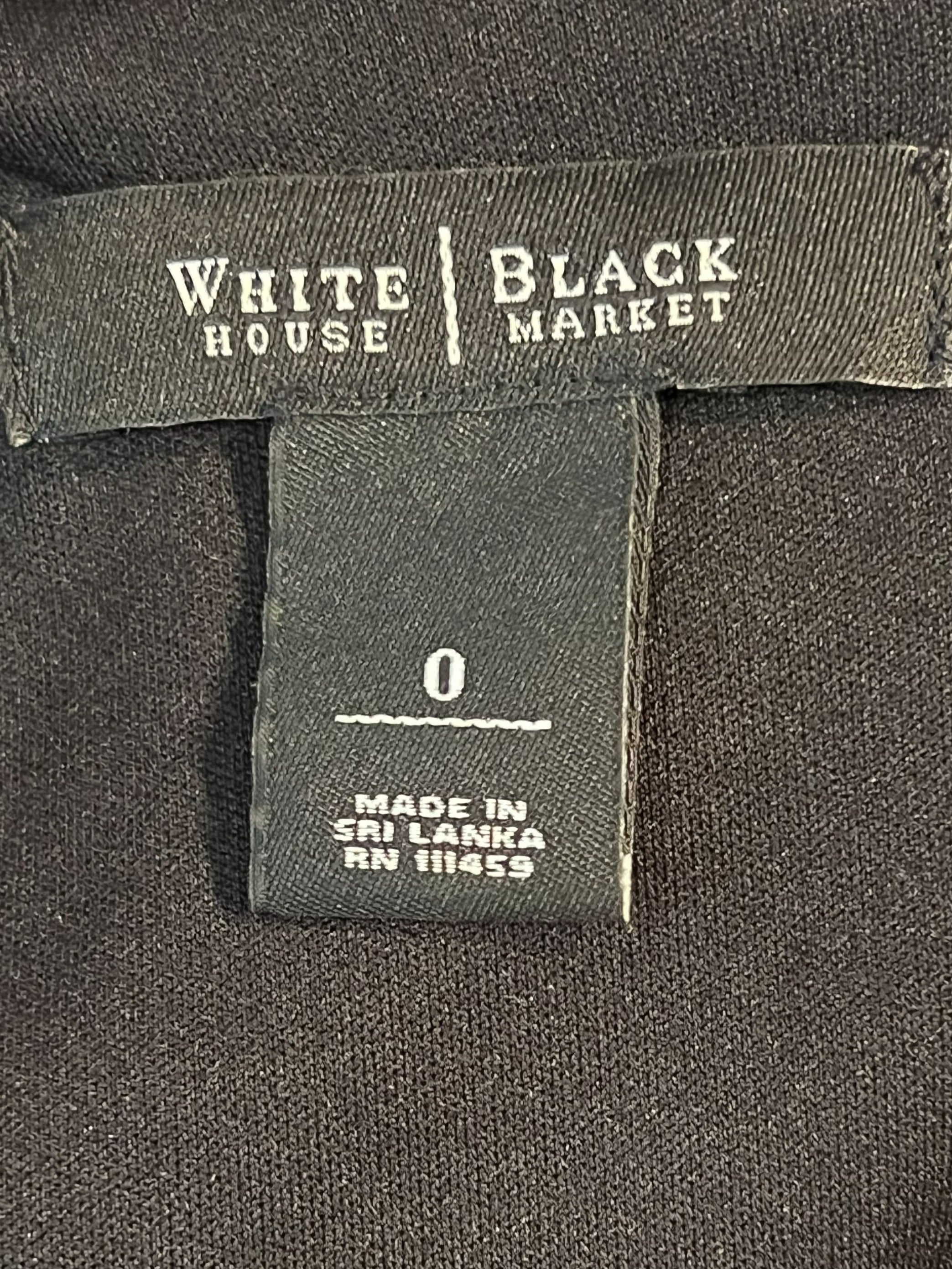 Close-up of a black garment's interior label area showing a size 0 tag and a vertical brand tag for White House Black Market.