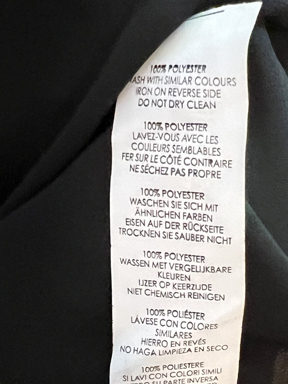 Close-up of a black garment's interior neck label with printed care instructions in French and English.