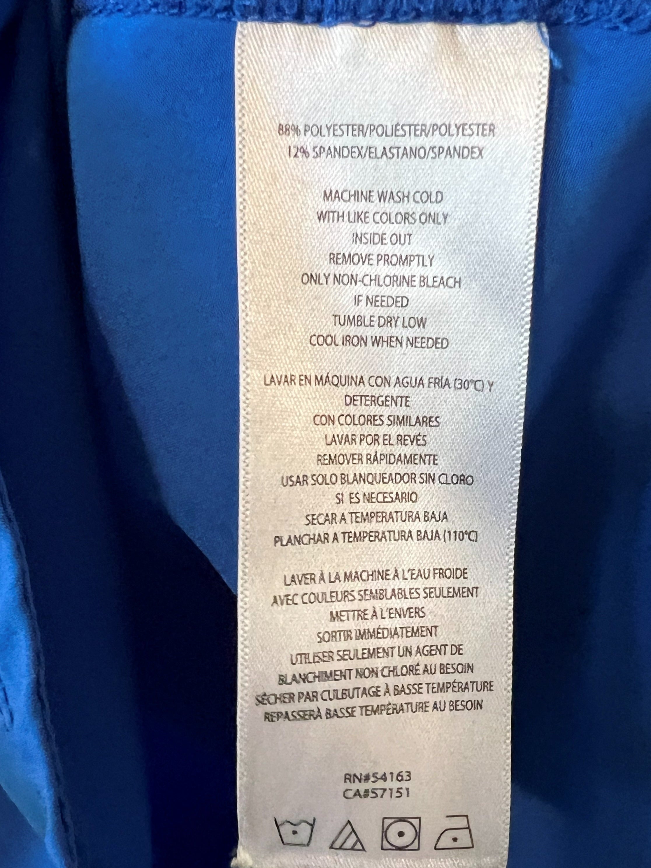 Close-up of the inside waistband of a bright blue tank, showing a white sewn-in care label with printed care instructions.