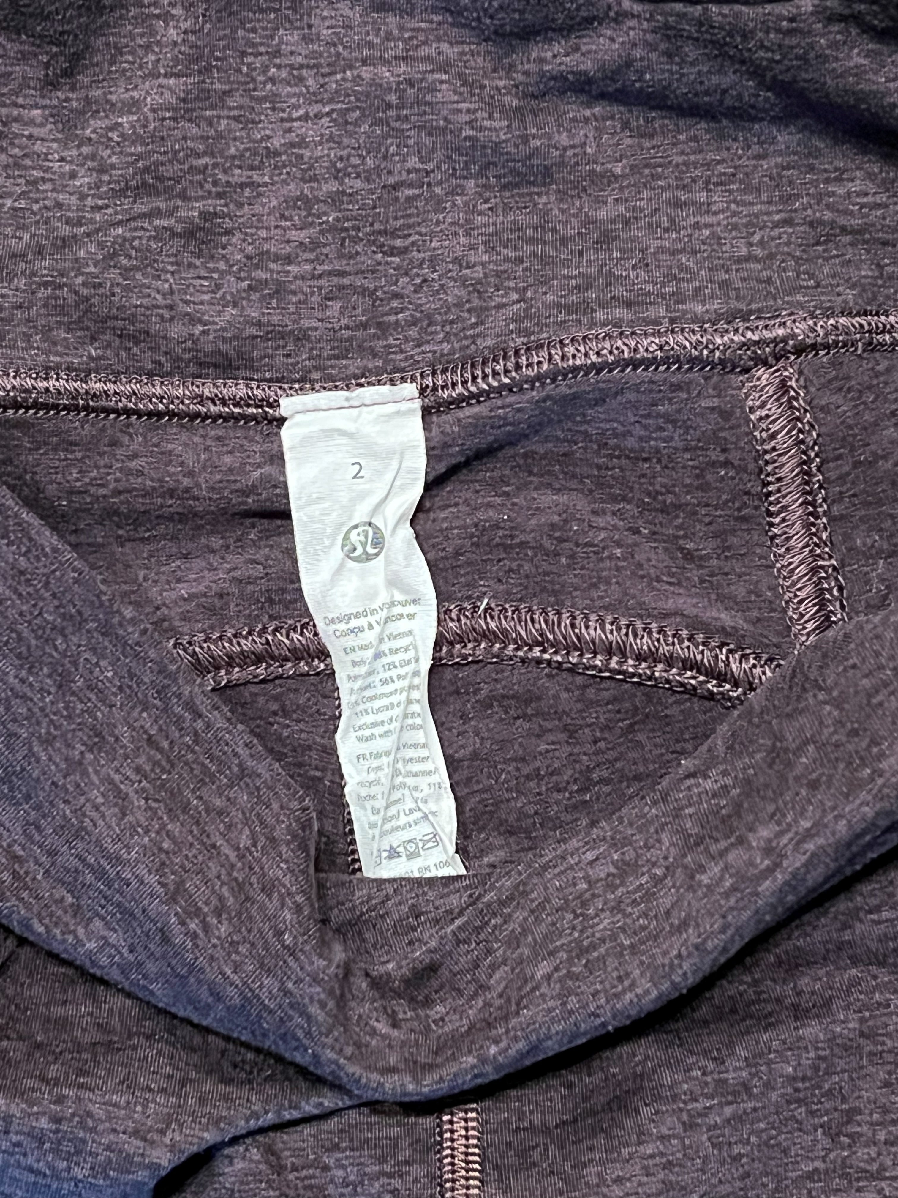 Close-up of a dark heathered gray athletic garment with a white sewn-in size tag showing a size 2.