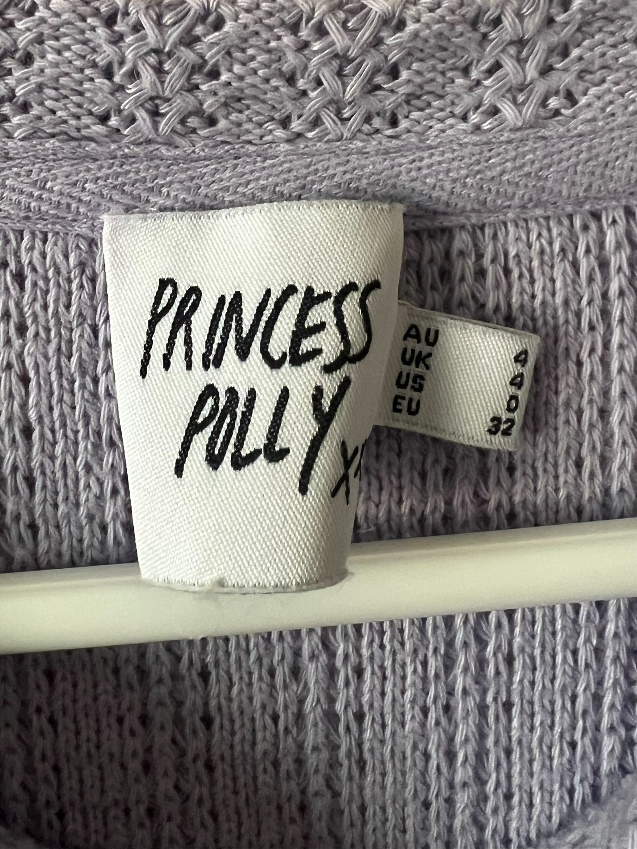 Close-up of a lavender knit garment showing the interior neck label with 'PRINCESS POLLY' written in black script.