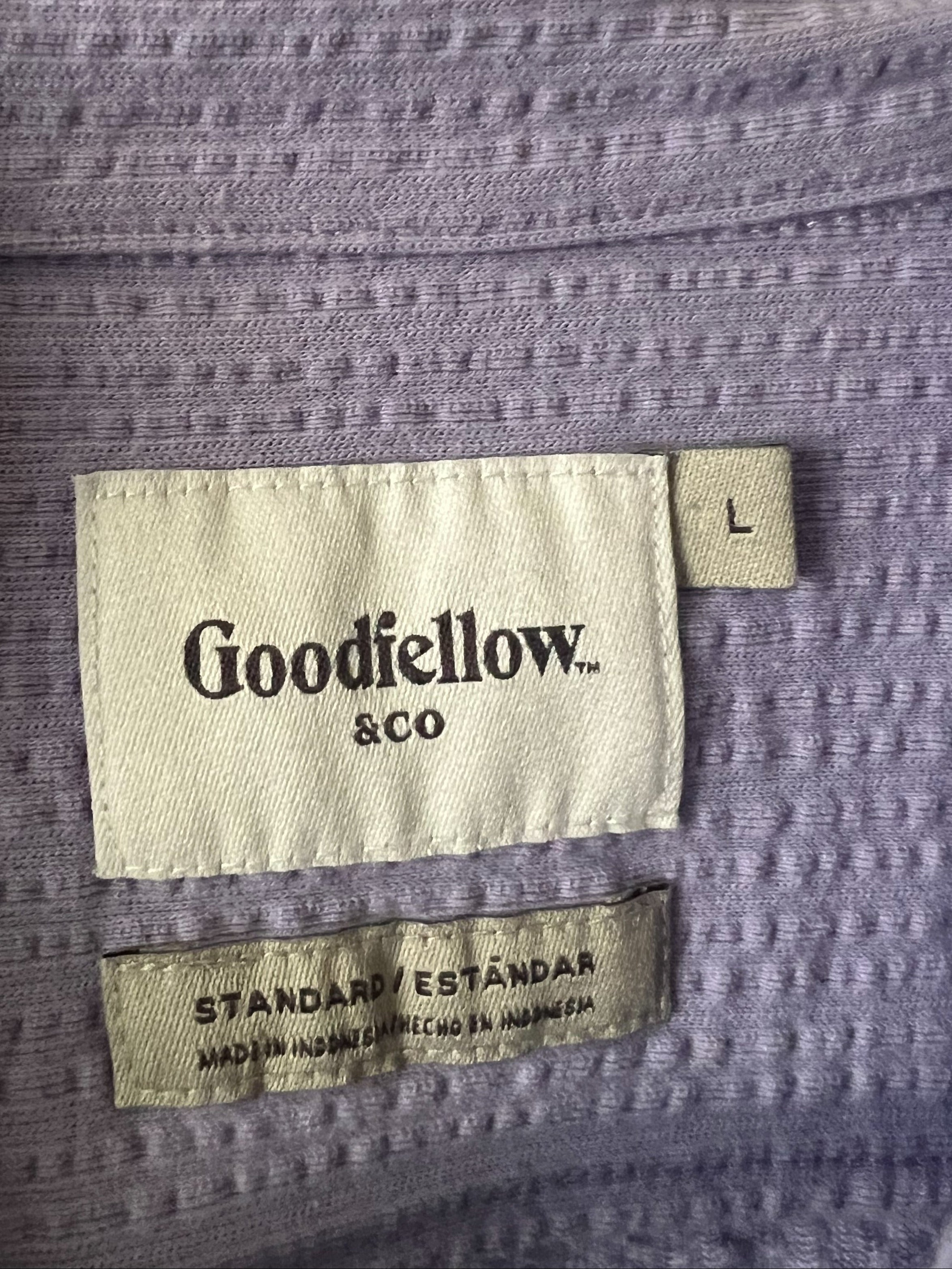 Close-up of a lavender waffle-knit garment hanging on a white hanger, showing a Goodfellow & Co brand label and a size tag marked L.